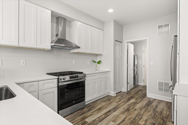 kitchen with dark wood finished floors, visible vents, gas range, and wall chimney range hood