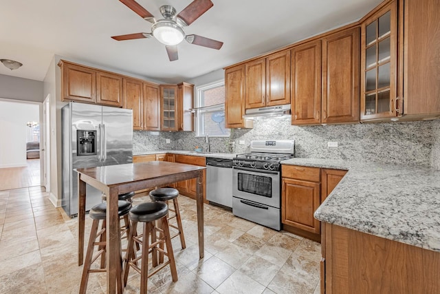 kitchen featuring stainless steel appliances, brown cabinets, and under cabinet range hood