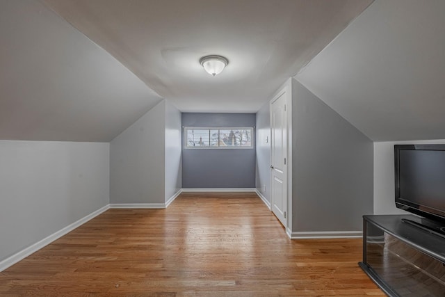 additional living space with light wood-type flooring, lofted ceiling, and baseboards