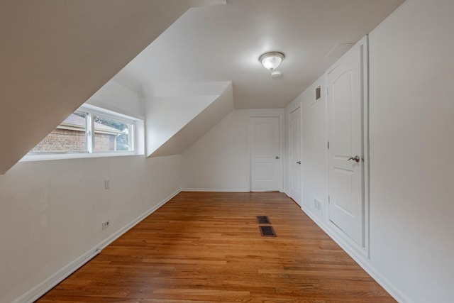 bonus room featuring light wood-style floors, visible vents, and vaulted ceiling