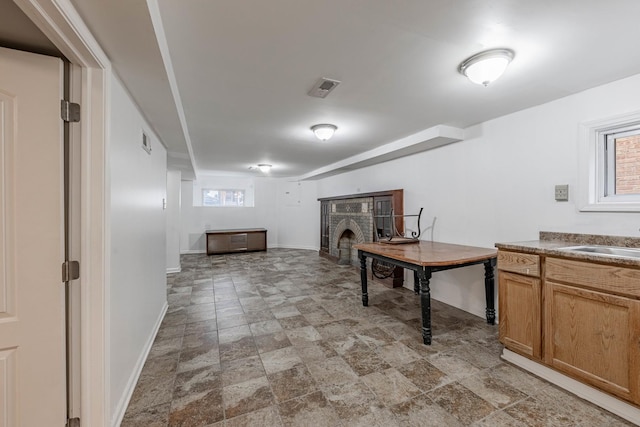 kitchen featuring baseboards, visible vents, a sink, and a fireplace