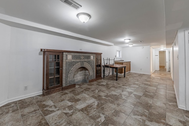 unfurnished living room featuring a brick fireplace, visible vents, and baseboards