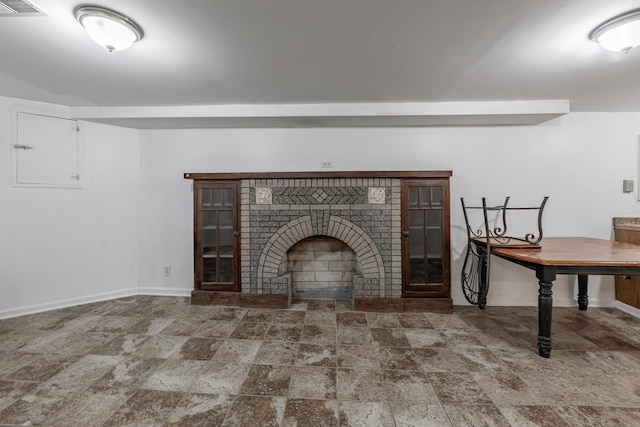 unfurnished living room with stone finish floor, baseboards, a fireplace, and visible vents