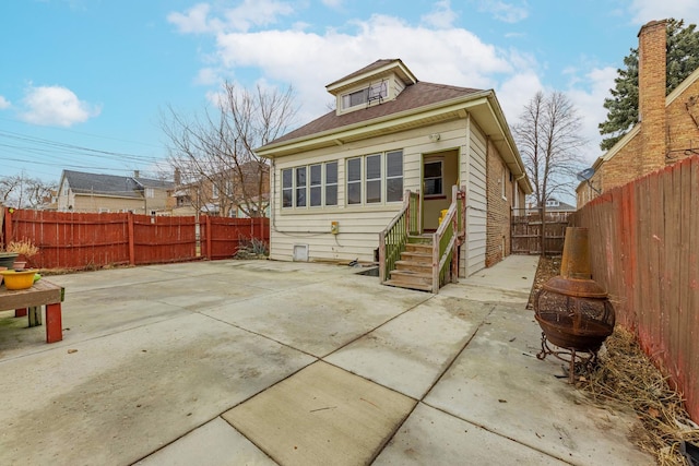 back of house with entry steps, a fenced backyard, and a patio