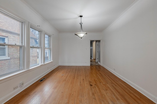 unfurnished dining area with light wood-style floors, baseboards, visible vents, and crown molding