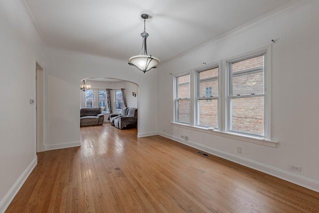 unfurnished dining area with arched walkways, light wood-type flooring, visible vents, and baseboards