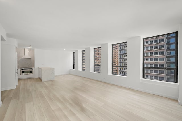 unfurnished living room featuring light wood-style flooring and baseboards