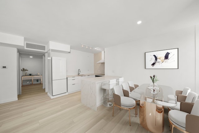 interior space with visible vents, freestanding refrigerator, white cabinetry, a sink, and a peninsula