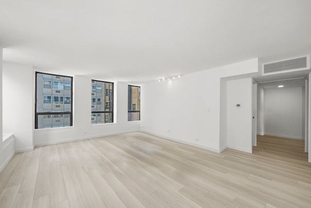 unfurnished room with light wood-style flooring, visible vents, and baseboards