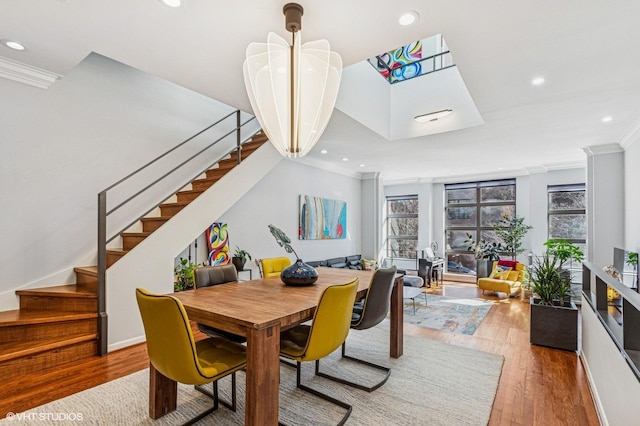 dining space with plenty of natural light, wood finished floors, stairs, and ornamental molding