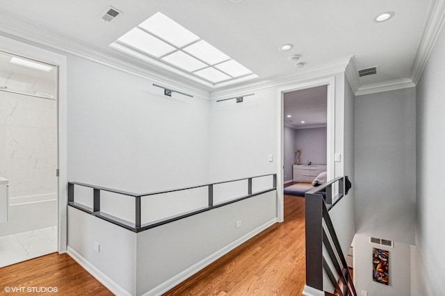 hall with crown molding, visible vents, and light wood-type flooring