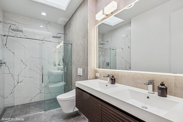 bathroom with a marble finish shower, toilet, a skylight, and a sink