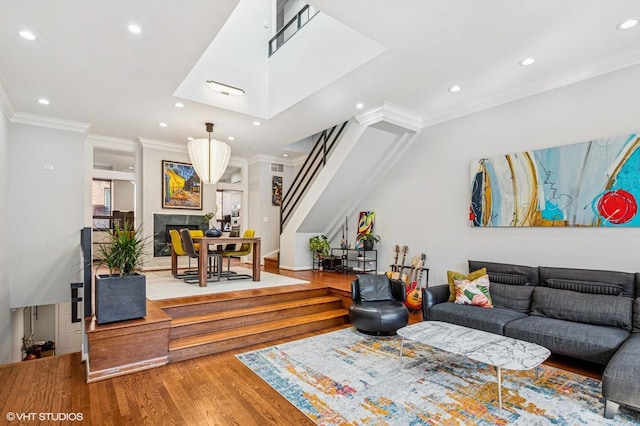 living room with a premium fireplace, wood finished floors, stairs, and ornamental molding