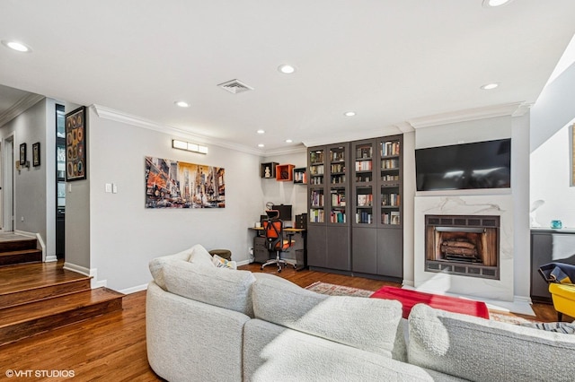 living area featuring visible vents, ornamental molding, recessed lighting, a fireplace, and wood finished floors