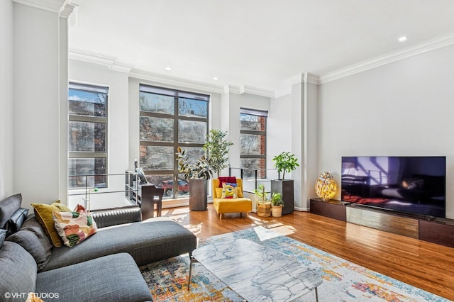 living room with a healthy amount of sunlight, ornamental molding, and wood finished floors