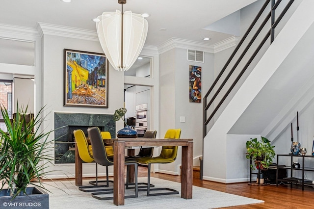 dining room featuring visible vents, crown molding, stairs, and wood finished floors