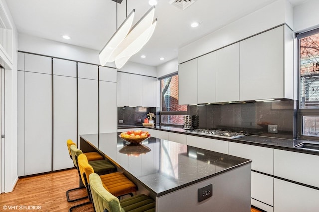 kitchen with visible vents, modern cabinets, a kitchen breakfast bar, white cabinetry, and light wood-style floors