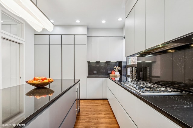 kitchen with light wood-style flooring, recessed lighting, stainless steel gas stovetop, white cabinetry, and tasteful backsplash