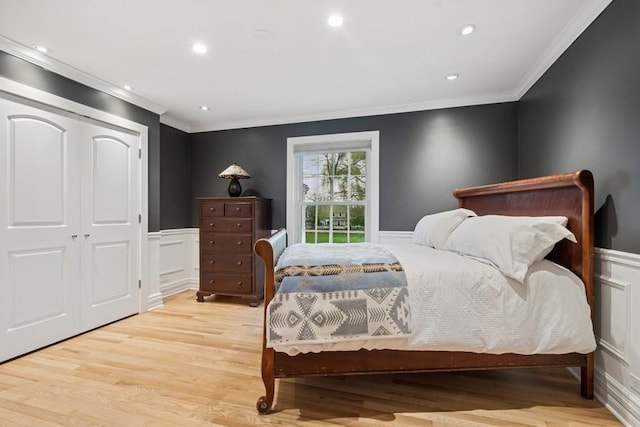 bedroom featuring crown molding, wainscoting, and light wood-style floors