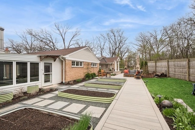 rear view of house with an outdoor living space, a fenced backyard, a yard, brick siding, and a wooden deck