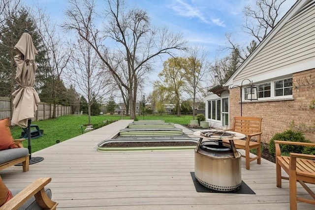 wooden deck featuring an outdoor fire pit, a fenced backyard, and a yard