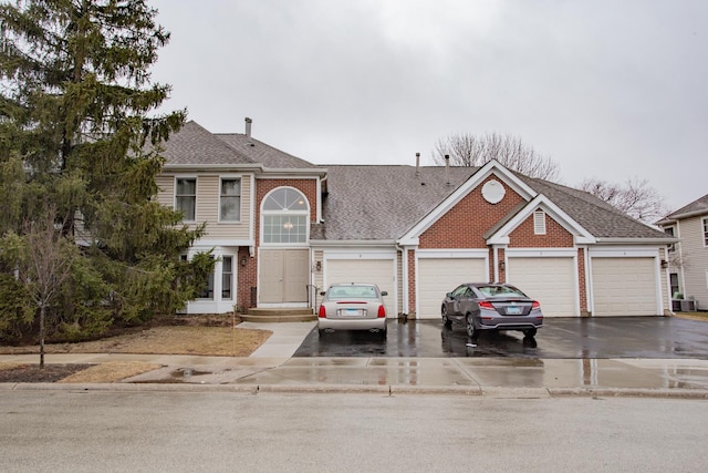 view of front of house with a garage, driveway, a shingled roof, and brick siding