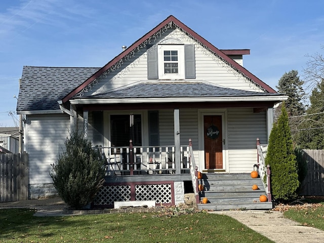 bungalow with fence, a porch, and roof with shingles