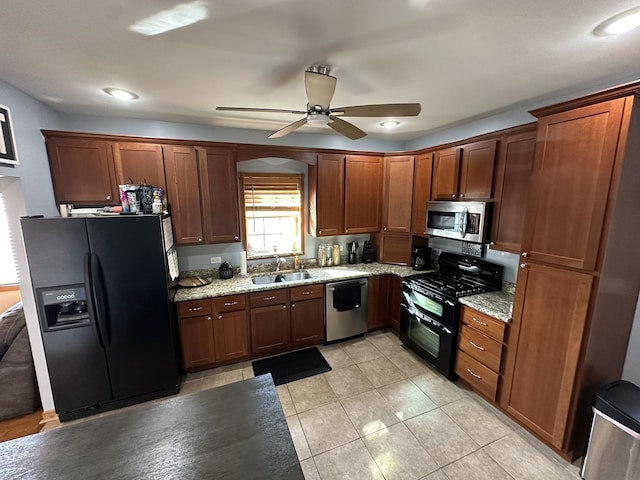 kitchen with light tile patterned floors, ceiling fan, light stone countertops, black appliances, and a sink