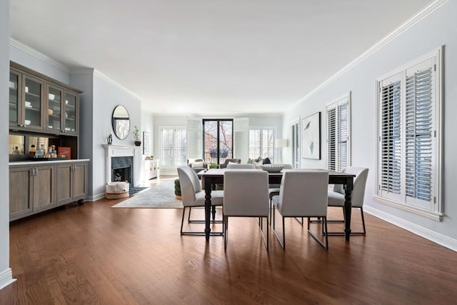 dining area with ornamental molding, dark wood finished floors, a high end fireplace, and baseboards