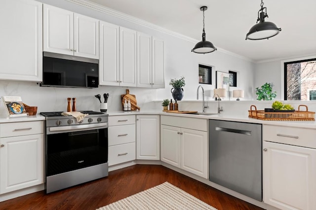 kitchen featuring appliances with stainless steel finishes, white cabinets, light countertops, and a sink