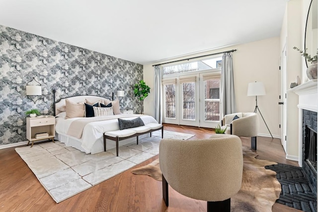 bedroom with baseboards, an accent wall, a fireplace, and wallpapered walls