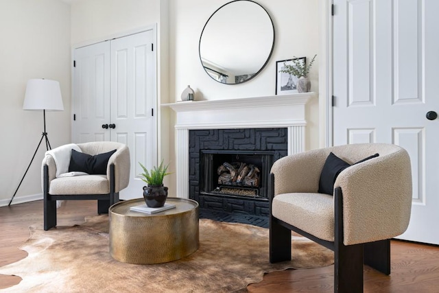 sitting room with a fireplace with flush hearth and wood finished floors