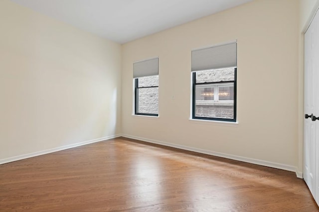 unfurnished room with baseboards and wood finished floors