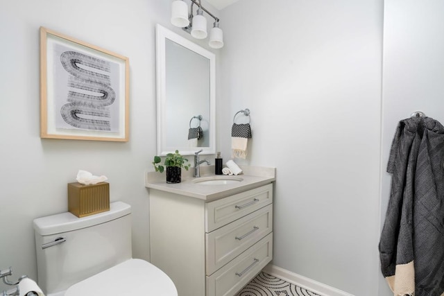 bathroom with vanity, toilet, and baseboards