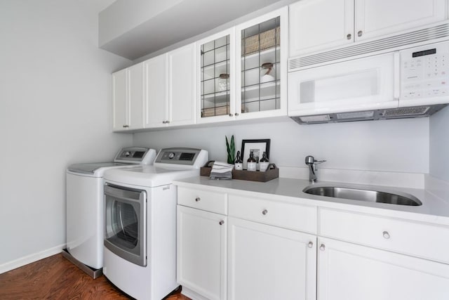 washroom featuring cabinet space, baseboards, dark wood-style flooring, separate washer and dryer, and a sink