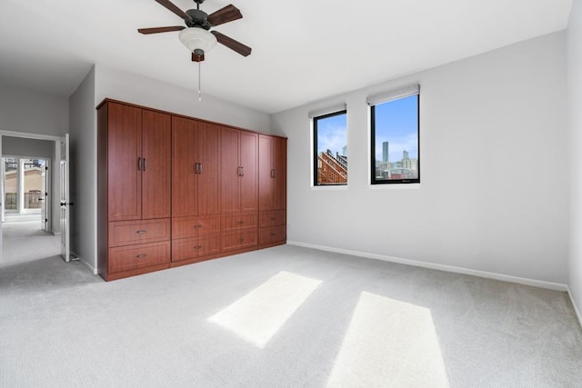 unfurnished bedroom featuring light carpet, ceiling fan, and baseboards