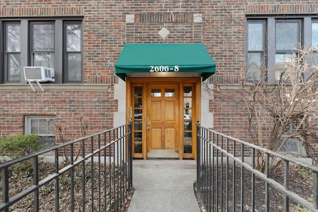 view of exterior entry featuring brick siding and cooling unit