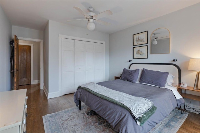 bedroom featuring a ceiling fan, a closet, baseboards, and wood finished floors