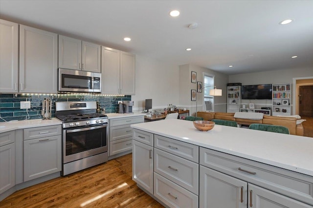 kitchen featuring tasteful backsplash, light wood-style flooring, appliances with stainless steel finishes, and light countertops