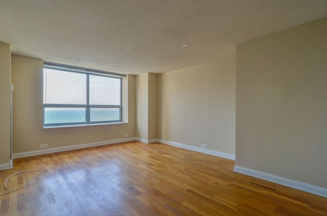 spare room featuring a textured ceiling, wood finished floors, and baseboards