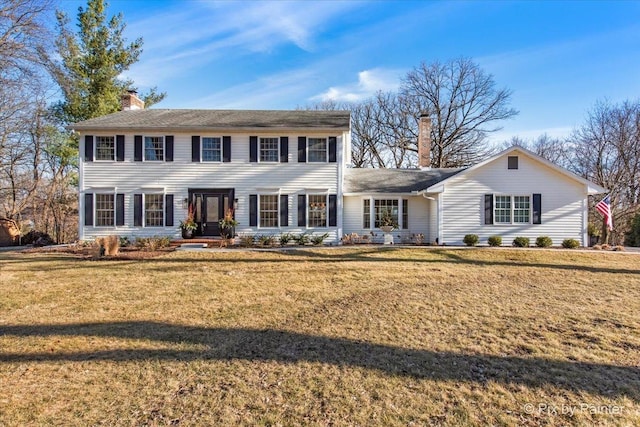 colonial inspired home featuring a front yard and a chimney