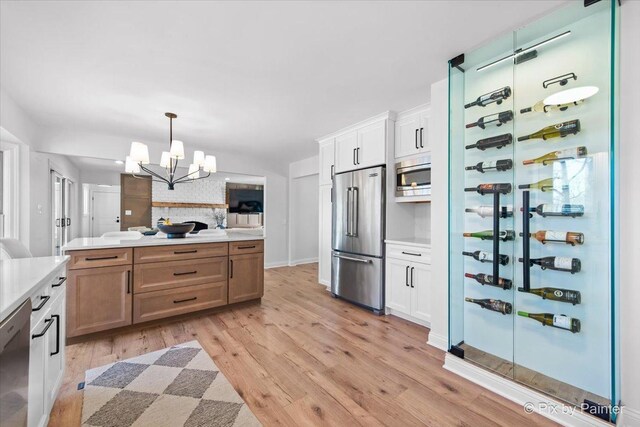 kitchen featuring light wood-style flooring, open floor plan, light countertops, appliances with stainless steel finishes, and decorative light fixtures