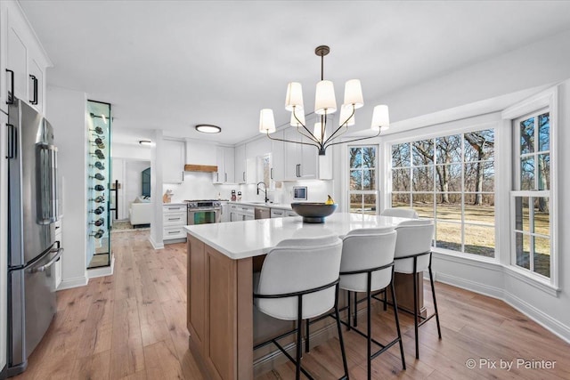 kitchen featuring stainless steel appliances, light wood-style floors, light countertops, and a sink