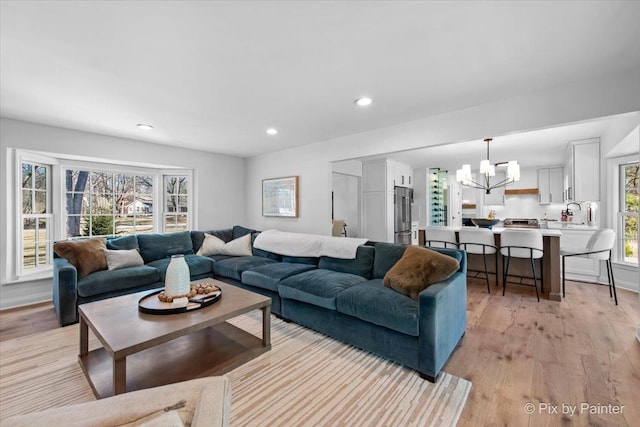 living room with recessed lighting, a notable chandelier, and light wood-style flooring