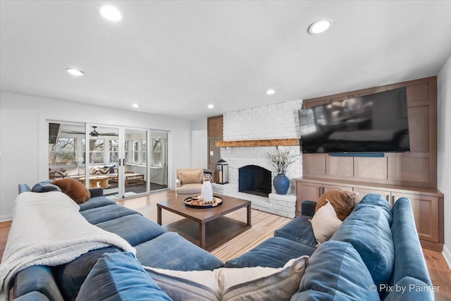 living room featuring recessed lighting, a brick fireplace, and wood finished floors