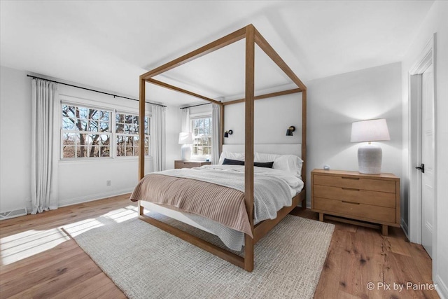 bedroom with baseboards, visible vents, and wood finished floors