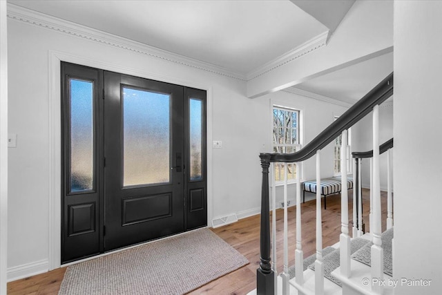 foyer entrance with baseboards, visible vents, wood finished floors, stairs, and crown molding