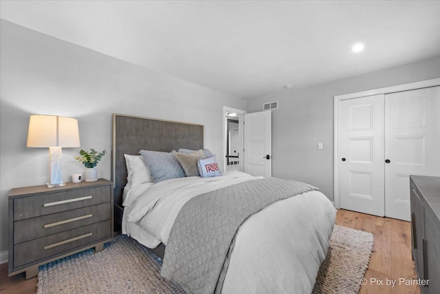 bedroom with light wood-style flooring, a closet, and visible vents