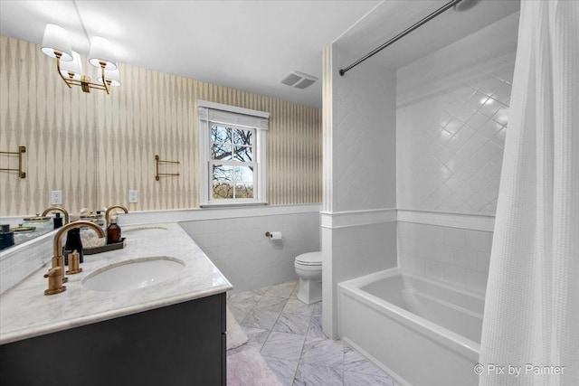 bathroom featuring visible vents, double vanity, a sink, and toilet