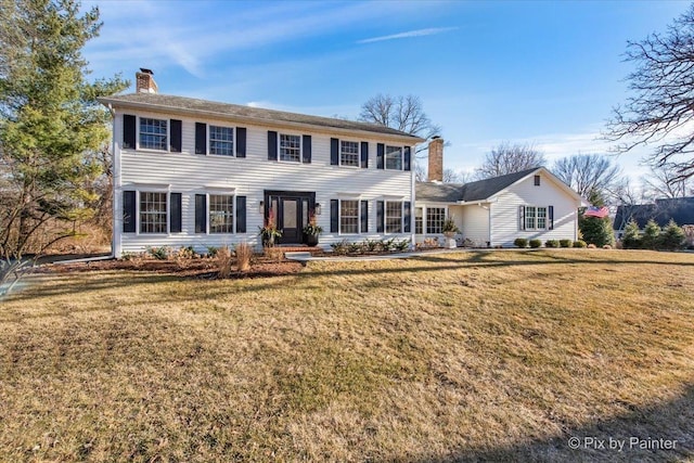 colonial home featuring a chimney and a front yard